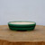 Shallow oval pot in glossy forest green on a natural wood slab