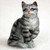 Miniature silver shorthaired tabby cat figurine seated with one front paw raised