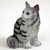 Miniature silver tabby Maine Coon cat figurine in a seated pose, long haired