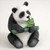 A charming panda bear figurine sculpted with realistic fur texture, designed as a decorative accessory for bonsai trees or miniature gardens. This miniature panda is depicted sitting upright, cradling a vibrant green bamboo stalk with detailed leaves as if it’s enjoying a snack. The figurine features the classic black-and-white giant panda markings, including the distinctive dark patches around its eyes, small black ears, and dark limbs contrasted against a white body. Its small scale and playful pose make it an ideal bonsai ornament for adding a touch of wildlife and whimsy to an indoor or outdoor miniature landscape.