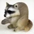 Miniature raccoon figurine in a hunched sitting pose, a decorative bonsai accessory
