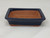 A 5-inch rectangular Yixing bonsai pot is presented against a clean, white background. The ceramic pot features a deep midnight blue glaze with a subtle sheen covering its exterior sides and wide top rim. In contrast, the interior and the small, integrated feet are left unglazed, showing the natural, textured reddish-brown color of the Yixing clay. The pot has a slightly flared silhouette with gently rounded corners and includes two visible drainage holes at the bottom of the interior to ensure healthy plant growth. This classic, small-sized bonsai pot is a functional and aesthetic choice for housing a miniature tree.