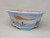 A hand-painted 10-inch Yixing bonsai pot featuring a classic landscape scene against a creamy white background. The ceramic pot has an elegant lobed oval shape with a wide, flared rim and small integral feet at the base. A fine network of crackle glaze, or crazing, covers the surface, adding an antique character to the piece.

The central artwork depicts a serene maritime landscape. In the foreground, two traditional sailing junks with brownish-red sails glide across light blue water detailed with dark blue ripples. Tiny figures of people are visible on the larger boat. To the left, a small green island or shoreline is visible, while a craggy, blue-toned mountain peak rises on the right. Across the pale blue sky, a large, wispy mountain range is rendered in soft brown washes, and small black silhouettes represent birds in flight. The top edge of the rim is accented with a simple decorative border of blue wavy lines and small red dots. This artisanal painted bonsai pot combines functional horticultural design with traditional East Asian landscape painting.