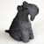 A detailed miniature figurine of a Kerry Blue Terrier dog, designed as a decorative accessory for a bonsai tree. The figurine is depicted in a sitting pose, with its head turned slightly to the right. It is crafted in a solid, dark charcoal gray color and features the breed's characteristic curly, textured coat, which is rendered with fine, wavy details across its entire body. 

The figurine captures the distinctive long muzzle with a thick "beard" and prominent eyebrows, along with small ears that fold forward over the head. A single small, black, glossy eye is visible, adding a lifelike quality to the piece. Set against a plain, off-white, slightly textured background, this miniature Kerry Blue Terrier statuette is a charming addition to an indoor bonsai display or a miniature garden scene, providing a touch of personality and scale.