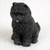 A detailed miniature figurine of a black Chow Chow dog, designed as a charming accessory for bonsai tree displays or fairy gardens. The figurine captures the breed's iconic stocky build and dense, textured black fur with realistic detail. Sitting in a classic pose, the black Chow Chow has small, rounded ears, dark eyes, and a slightly open mouth showing a tiny hint of its tongue. This decorative figurine is shown against a neutral, off-white background, highlighting its intricate craftsmanship and suitability for enhancing the aesthetics of a miniature landscape.