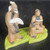 Chinese mud man figurine of two men reading and talking on a lime green base