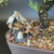 Chinese mudman fisherman figurine nestled at the base of a bonsai tree