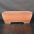 A front-facing, eye-level photograph of a 14-inch rectangular unglazed Yixing bonsai pot (model YX1094) from Bonsai Outlet. The pot is expertly crafted from authentic reddish-brown Yixing clay, exhibiting a smooth, matte, and non-reflective finish. Its classic rectangular design features soft, rounded corners and sides that subtly taper downward towards a decorative raised band just above the base. The vessel is supported by four solid, rectangular block-style feet at each corner, providing the necessary elevation for proper drainage and airflow essential for bonsai health. The pot sits on a dark, textured surface against a minimalist dark grey backdrop, which highlights its clean lines, warm earthy tones, and elegant proportions.