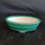 Oval green glazed Yixing pot on a dark textured wooden surface
