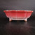 Side profile of the round red glazed Yixing pot with a scalloped design