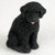 A detailed, lifelike miniature figurine of a solid black Portuguese Water Dog, specifically designed as a decorative accent for bonsai trees, terrariums, or miniature gardens. The figurine depicts the dog in a sitting pose, showcasing the characteristic thick, curly coat of the breed with a realistic, tactile texture. 

The dog’s face is finely detailed with dark, gentle eyes and a tiny pink tongue playfully peeking out from its mouth. Its ears are folded down in a soft, natural position, adding to its charming and lifelike appearance. The small scale of the statue makes it an ideal accessory for bonsai enthusiasts looking to add a personalized touch to their indoor trees or for dog lovers seeking a small collectible. The figurine is set against a plain, light-colored background that highlights the intricate craftsmanship and deep black color of the piece.