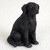 A highly detailed miniature figurine of a Flat-Coated Retriever dog, specifically designed as a decorative accessory for bonsai trees or miniature gardens. The figurine is depicted in a classic sitting pose, facing slightly toward the right. It is entirely black, featuring intricate molded textures that realistically represent the breed’s characteristic long, flowing, and slightly wavy coat. The small dog has floppy ears and lifelike eyes that give it an alert and loyal expression. Set against a soft, textured white background, the figurine's clean craftsmanship is highlighted, demonstrating how it can add a sense of life, scale, and personal flair when placed within a bonsai pot or indoor garden display.