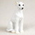 A detailed miniature figurine of a white Whippet dog, specifically designed as a decorative accent for bonsai trees or miniature fairy gardens. The figurine captures the elegant, slender build of a sighthound, shown in a calm sitting posture with its front legs straight and its tail neatly curled around its side. 

The Whippet has a bright white coat with subtle, hand-painted tan shading on the tips of its folded "rose ears" and around its paws. Its face is characterized by large, expressive black eyes, a small black nose, and a gentle expression. The surface of the figurine features finely sculpted textures to mimic the look of short fur. The dog is photographed against a soft, neutral off-white background, emphasizing its clean lines and delicate features, making it a perfect small-scale accessory for garden displays or pet-themed dioramas.