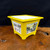 Yellow square pot with a calligraphy panel beside a painted landscape