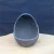 Front view of the charcoal-black egg-shaped planter on a light tan surface