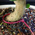 Close-up of Fukien Tea bonsai trunk base showing mature textured bark, bonsai soil surface, cream ceramic pot rim, and red TWEB23003 identification tag