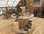 Collection of rare hand-fabricated steel bonsai sculpture pots by Benjamin Keating displayed on a round wooden table inside the Bonsai Outlet greenhouse