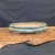 An elegant, shallow, oval-shaped Yixing bonsai pot is showcased in a side-angle photograph. The ceramic planter features a glossy, sea-foam green glaze with a soft, reflective finish and subtle crazing. It has a classic double-lipped rim and a lobed silhouette, resting on four small, decorative cloud-style feet.