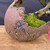 Close-up of the handmade crescent pot showing its curved opening, rough brown clay surface, raised textures, natural-looking cracks, and moss.