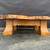 Low close-up of the bonsai stand’s quartersawn white oak base, flared legs, decorative lower edge and thick natural-edge olivewood burl top.