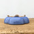 Underside of the glazed ceramic pot on a light brown wooden surface