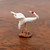 A detailed, handcrafted Chinese mudman figurine of a white crane in a dynamic, soaring pose. The ceramic bird features a matte white body with elegantly swept-back wings that show subtle texture and aged speckling. Its long, slender neck curves forward, topped with a bright red spot on its head and a thin, brownish beak. Supporting the bird are two delicate, copper-toned wire legs rooted into a small, textured reddish-brown clay base. The figurine is positioned on a polished dark wood surface with visible grain, illustrating its use as a traditional decorative accent for bonsai or indoor gardens. This miniature crane, often a symbol of longevity and grace, embodies the classic style of Mudmen figurines.