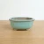 Celadon green glazed Japanese bonsai pot from the front on a light oak table