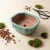 Empty celadon green glazed bonsai pot on a light table with bonsai soil, moss and pruning shears