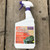 A 32-ounce white spray bottle of Bonide Liquid Copper Fungicide sits vertically on a rustic, weathered wooden plank surface. The bottle has a purple spray nozzle and trigger. The large label on the front features bold orange and white lettering that reads "LIQUID COPPER FUNGICIDE" and specifies it is "Ready to Use." A purple logo for the brand "BONIDE" is in the top right corner of the label, along with a seal stating "FOR ORGANIC GARDENING." The bottom right of the label includes illustrations of leaves affected by common plant diseases like Powdery Mildew, Black Spot, Early Blight, and Downy Mildew. Small text at the bottom indicates safety warnings and the active ingredient, Copper Octanoate.