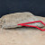 Bonsai root hook lying on a sandy surface in front of a large grey rock