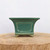 Rectangular pot in glossy teal-green glaze on a natural wood slab