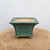 Front view of the square teal-green glazed pot with a flared rim