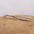 Tinyroots root rake and tweezer tool lying across a light circular wood slab
