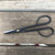 Top-down view of professional bonsai shears on a weathered wooden surface