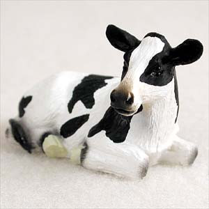 A detailed figurine of a black and white Holstein cow lying down in a restful pose. The miniature cow ornament features classic large black patches on a white body and head, with a tan-colored muzzle and attentive ears. Designed as a decorative accent for bonsai trees, the figurine has a subtle texture to mimic fur.