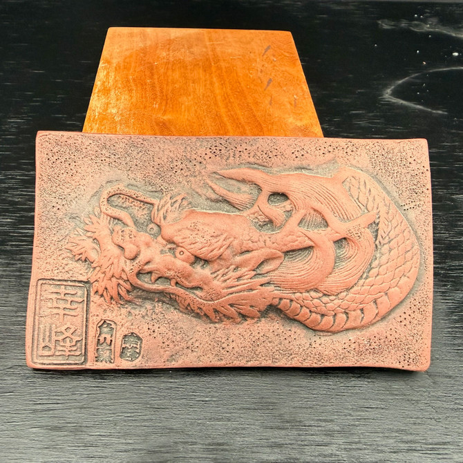 Front view of Kouji Watanabe Tokoname clay plaque showing hand carved dragon relief and maker marks in unglazed red clay