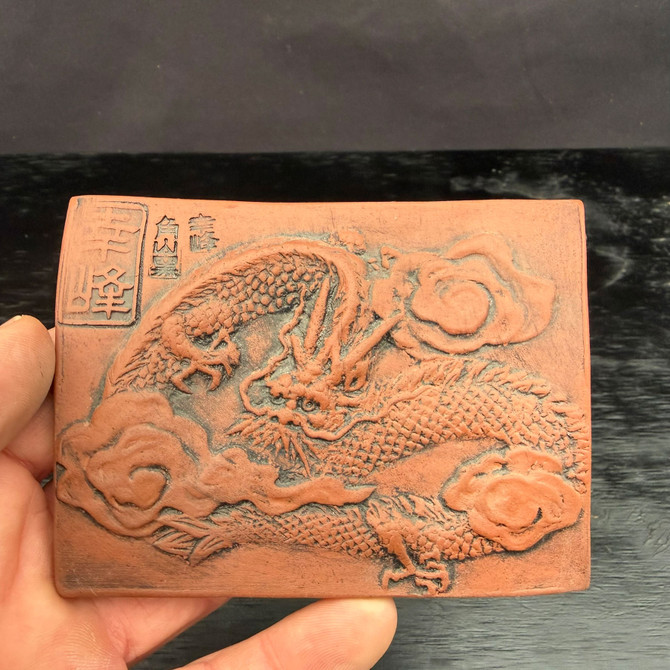 Tokoname clay dragon plaque shown in hand for size reference, compact unglazed red clay relief tile for bonsai display