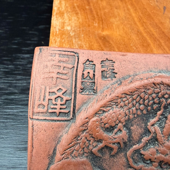 Close-up of Tokoname dragon plaque showing maker stamps and carved characters with darkened contrast in the relief