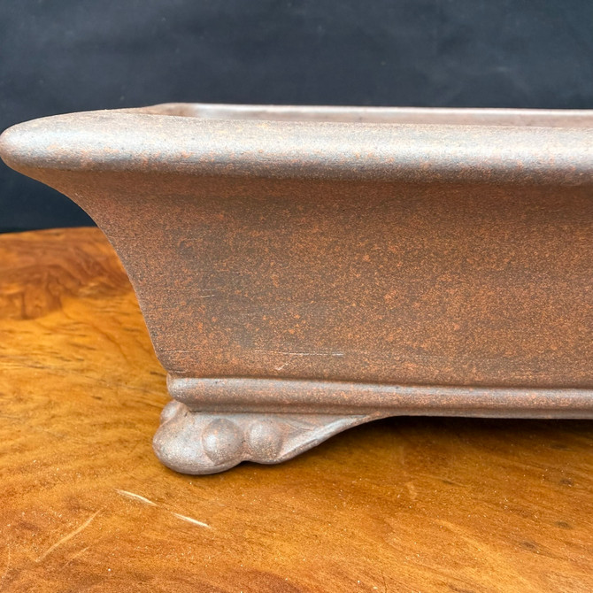 Close-up side detail of Reiho unglazed bonsai pot showing reddish-brown clay and carved foot
