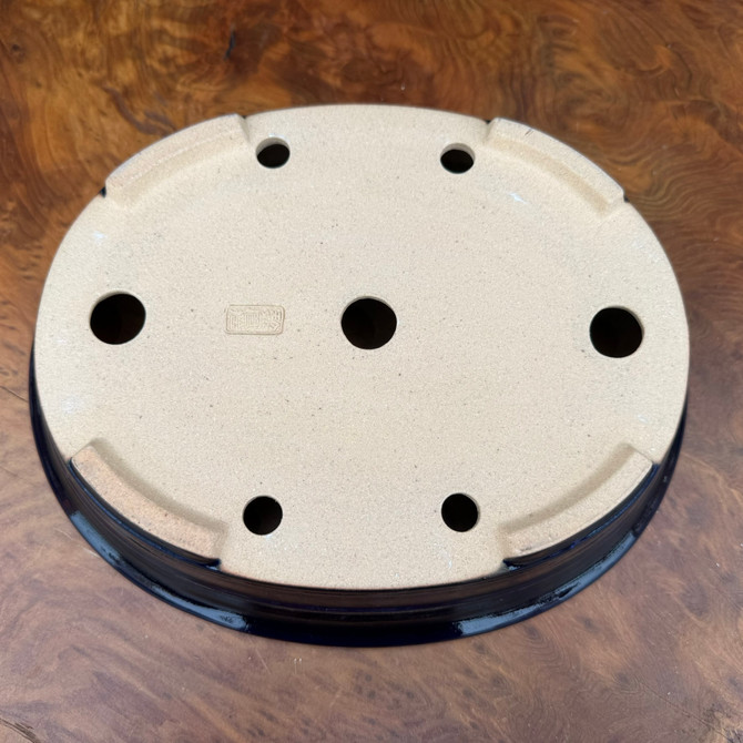 Underside view of dark blue glazed oval Reiho Tokoname bonsai pot showing drainage holes and foot structure
