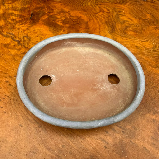 Top view of vintage oval unglazed bonsai pot showing shallow interior and drainage holes
