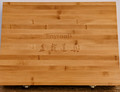 A top-down view of a rectangular, light-brown bamboo storage box designed for the Tinyroots Ultimate Package Stainless Steel Bonsai Tool Kit. The box is made from narrow bamboo strips, showing a clear horizontal grain and characteristic dark nodes. Centered on the lid is the "Tinyroots" brand name engraved in a serif font under a minimalist, thin arced line. Beneath the brand name are four larger, traditionally engraved Chinese characters, 盆栽道具, which translate literally to "bonsai tools." Two small silver metal latches are visible along the bottom edge of the box, which rests on a dark, textured surface. The overall appearance is professional and elegant, reflecting the high-quality nature of the bonsai tools inside.