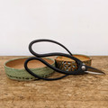 An elegant pair of Tinyroots carbon steel bonsai shears with sleek black handles and sharp, pointed metal blades rests atop two small, handcrafted ceramic pots. The shears, known for their precision in pruning, feature large, rounded loops for a comfortable and controlled grip. 

One of the ceramic pots is a shallow dish with a speckled sage-green glaze, while the other is a slightly deeper bowl featuring a textured exterior with an intricate pattern of earth-toned and green glazes. These artisanal pieces are displayed on a rustic, weathered wooden tabletop against a clean, minimalist white background. This professional product photograph highlights the high-quality craftsmanship of the carbon steel tools and ceramic accessories included in the Tinyroots Ultimate Package bonsai tool kit.
