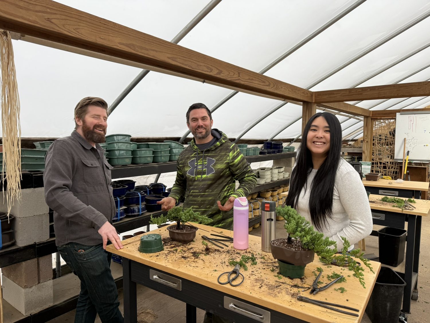 Students shaping their trees at a workbench during a bonsai workshop in the greenhouse