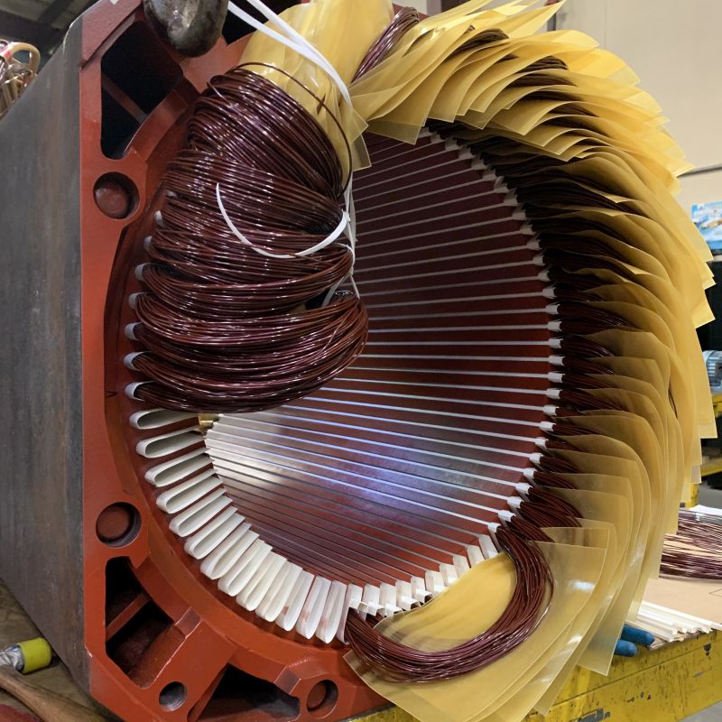 Three phase electric motor being rewound with insulation between each coil