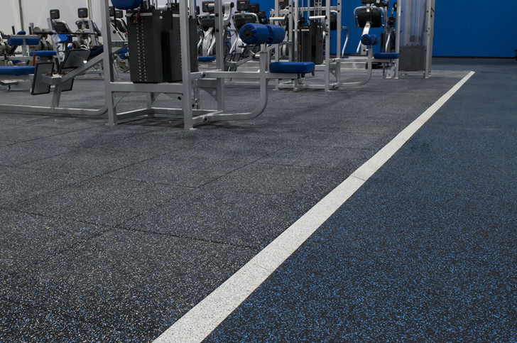 Close-up gym view of  Performance UltraTile in black with blue speckle, transitioning into a training lane marked with a white line