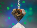 Close-up of Starry Night pendulum showing layers of white tea leaves, rose petals, blue cornflowers, saffron, and flecks of silver leaf inside resin.