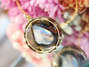Close-up of AAA Rainbow Moonstone New Moon pendant showing blue rainbow flash and gold frame