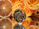 Angled view of handmade purple labradorite necklace showing the heart-shaped gemstone, black tea botanicals and layered resin design.