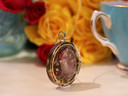Side view of round Rose Quartz and White Tea pendant showing the dimensional stone, botanical layers and gold-tone frame.